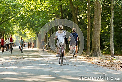 A young blond woman and man cyclingÂ in a sunny and green Amsterdam Vondelpark Editorial Stock Photo